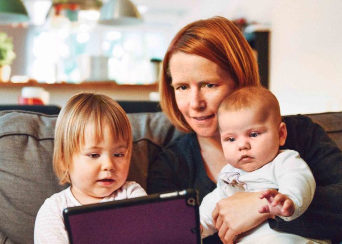 mom looking at a tablet with her kids at home