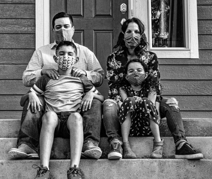 family sitting on their front porch with masks