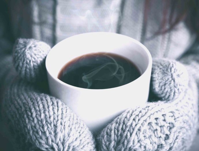 woman holding hot beverage with mittens on