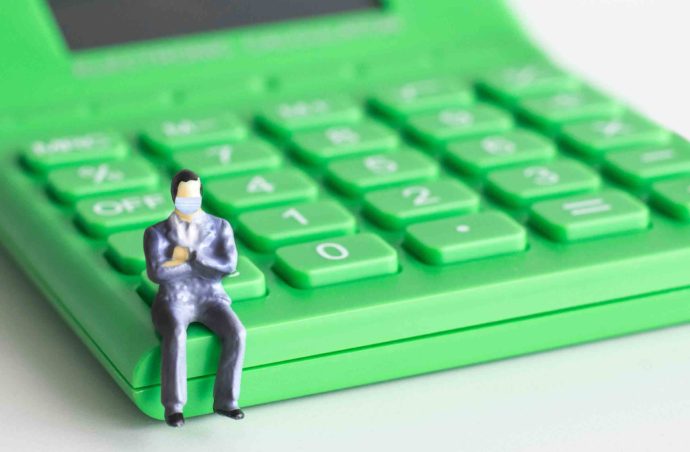figurine man with a face mask sitting on a calculator
