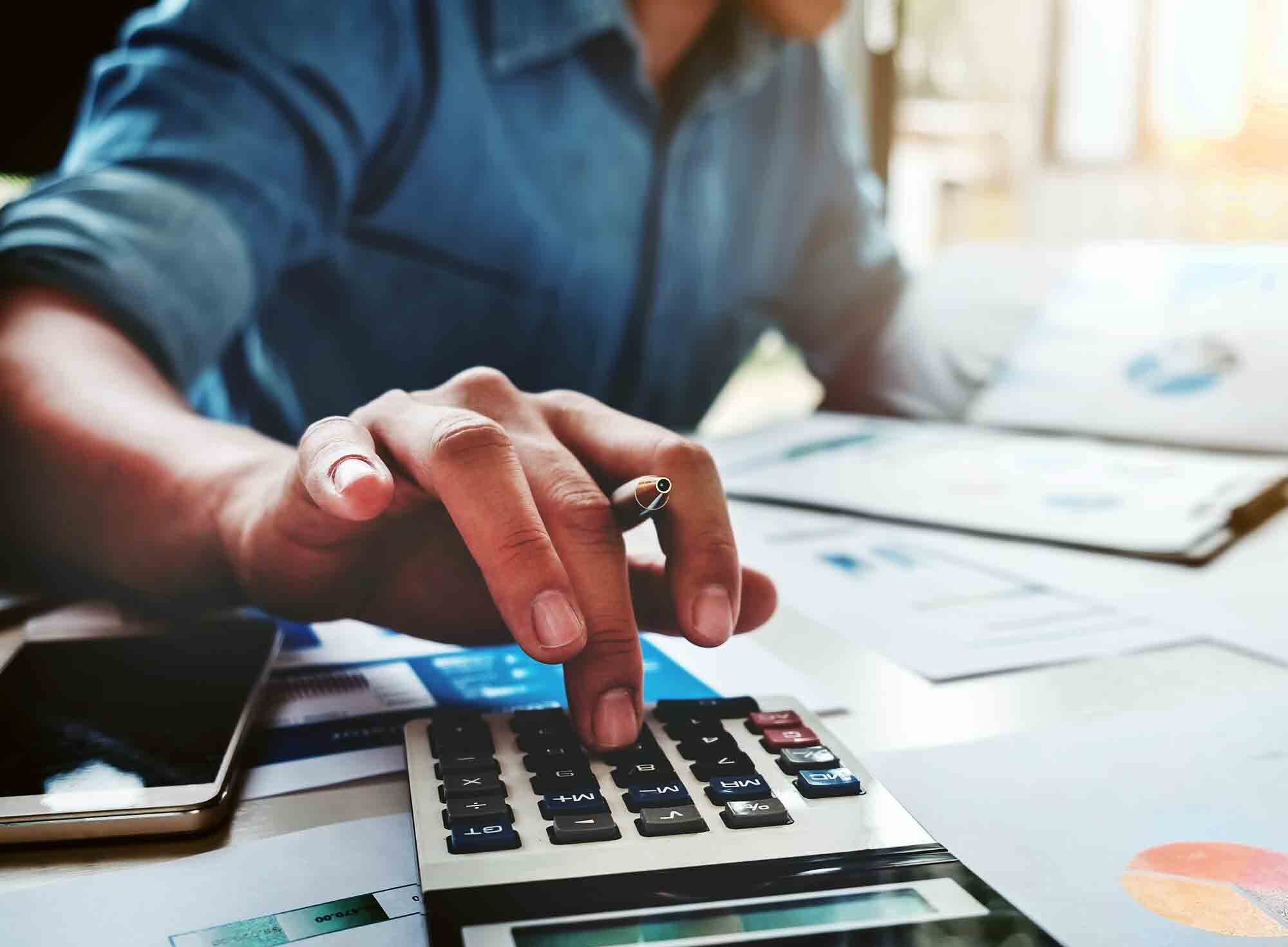 Man reviewing financial reports while using a calculator