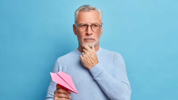Man thinking while holding paper airplane