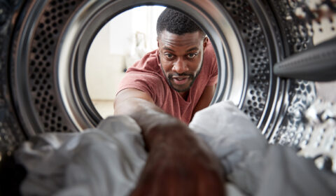 Man reaching into laundry machine for sheets