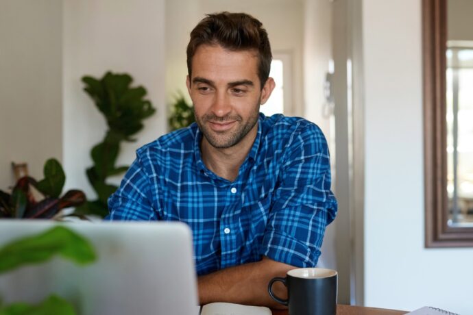 homeowner on computer in his home while drinking a cup of coffee